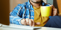 A man navigates a tablet computer with a cup of coffee.