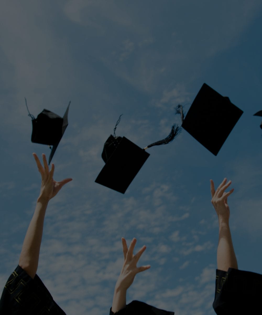 Graduates in black gowns celebrate their education advancement by throwing mortarboards into a blue sky with scattered clouds, embodying the best practices of modern achievement.