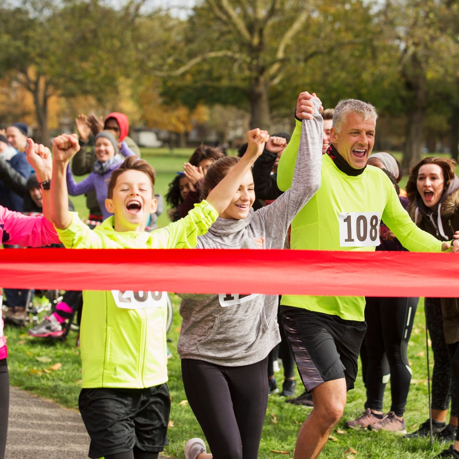 A group of runners, including a smiling man and two children, cross the red finish line holding hands as cheering spectators celebrate—capturing the teamwork and spirit highlighted in this nonprofit case study.